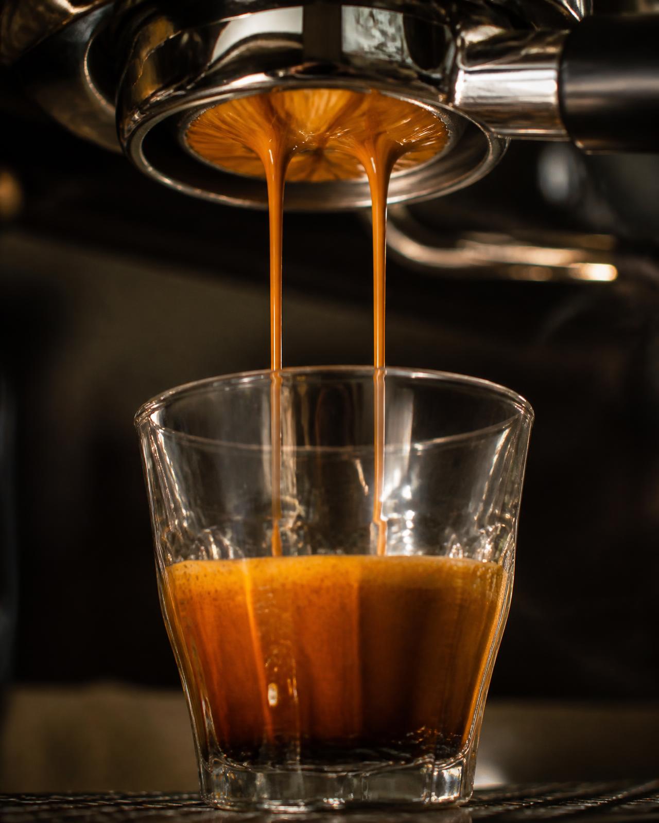 Close-up of espresso extracting from a bottomless portafilter into a glass